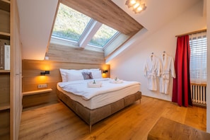 A bedroom with a skylight, a bed with white linens, two bedside tables with lamps, and a red curtain. - Sky Penthouse with matterhorn view (Zermatt)