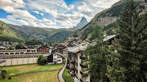 A mountain village with traditional buildings, a winding road, and a prominent mountain peak in the background. - Sky Penthouse with matterhorn view (Zermatt)