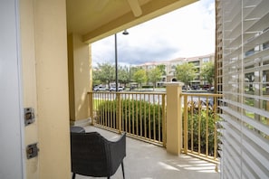 A balcony with a chair, a railing, and a view of a residential area with parked cars and buildings. - Vista Cay near Epic Apartment remodeled (Orlando)