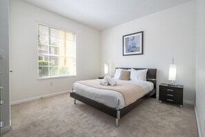 A bedroom with a bed, bedside tables, a window, and a framed picture on the wall. - Vista Cay near Epic Apartment remodeled (Orlando)