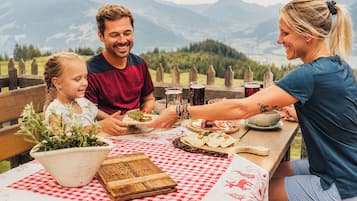 Eine Familie isst draußen mit Blick auf die Berge.