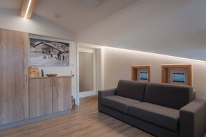 Una sala de estar moderna con un aparador de madera, un sofá gris y un cuadro colgado en la pared.