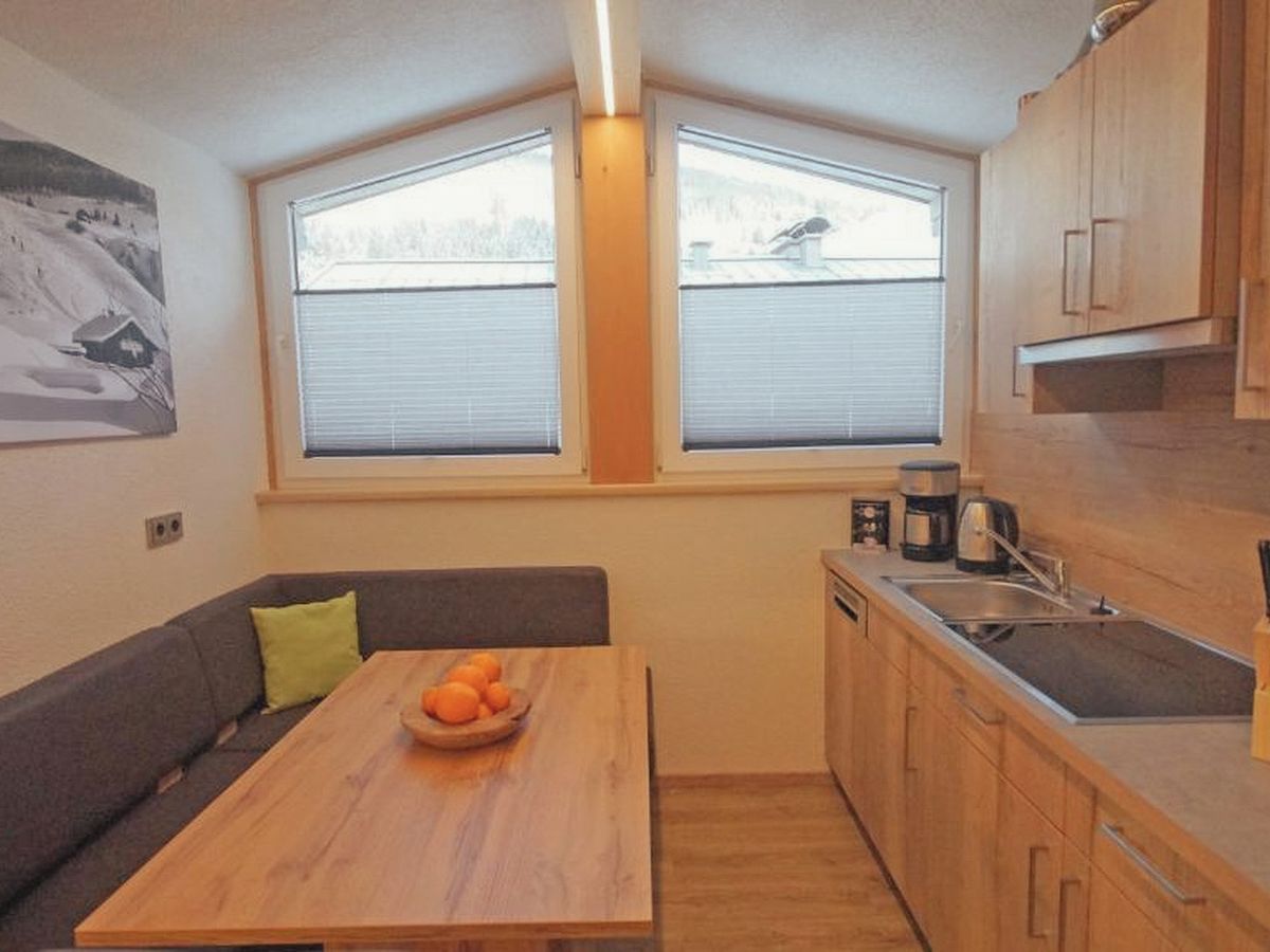 Eine kompakte Küche mit Essbereich, Holzschränken und einem Fenster mit Jalousien.