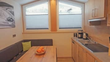 Eine kompakte Küche mit Essbereich, Holzschränken und einem Fenster mit Jalousien.