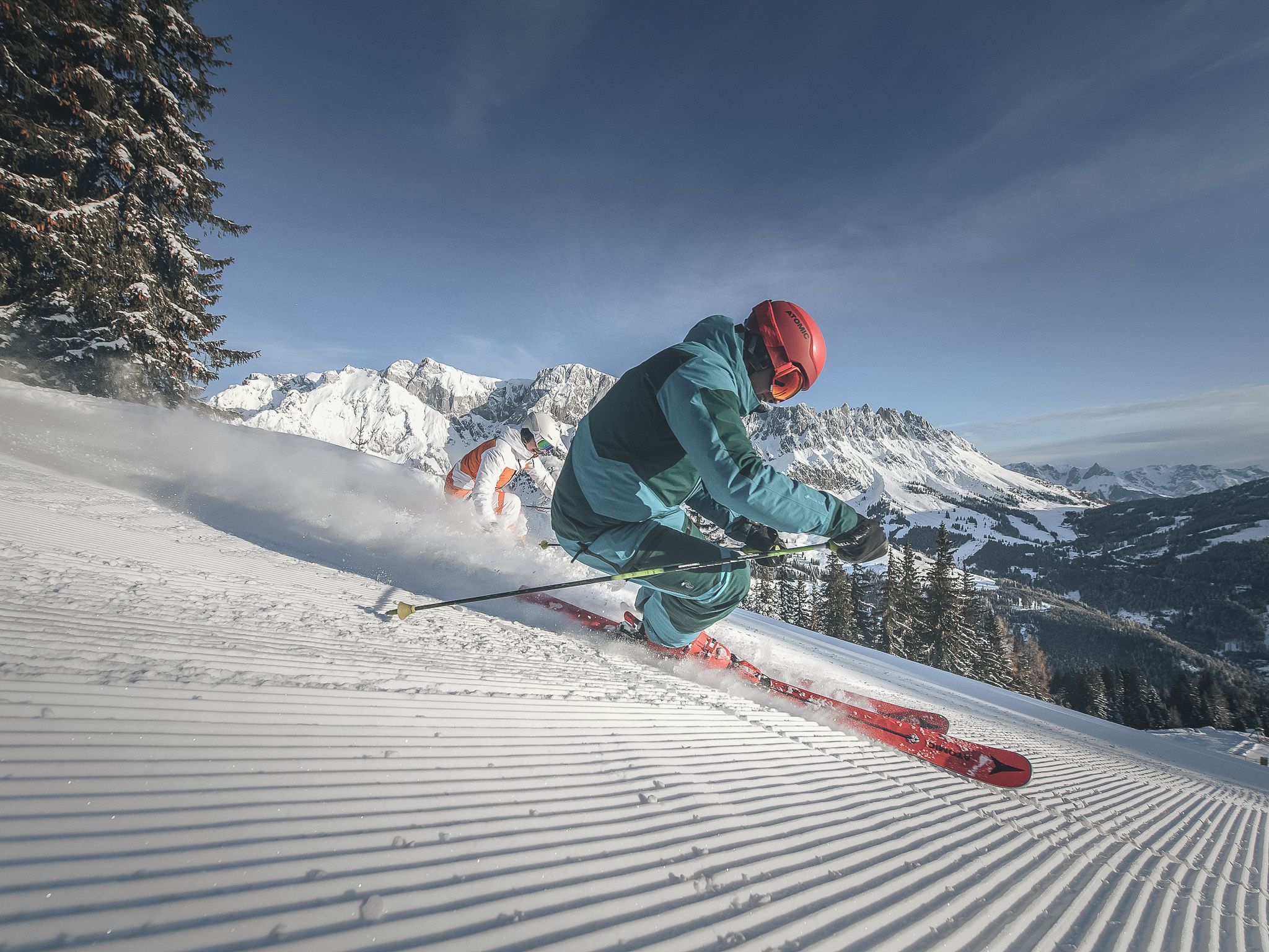A skier on a snowy slope with mountains in the background.