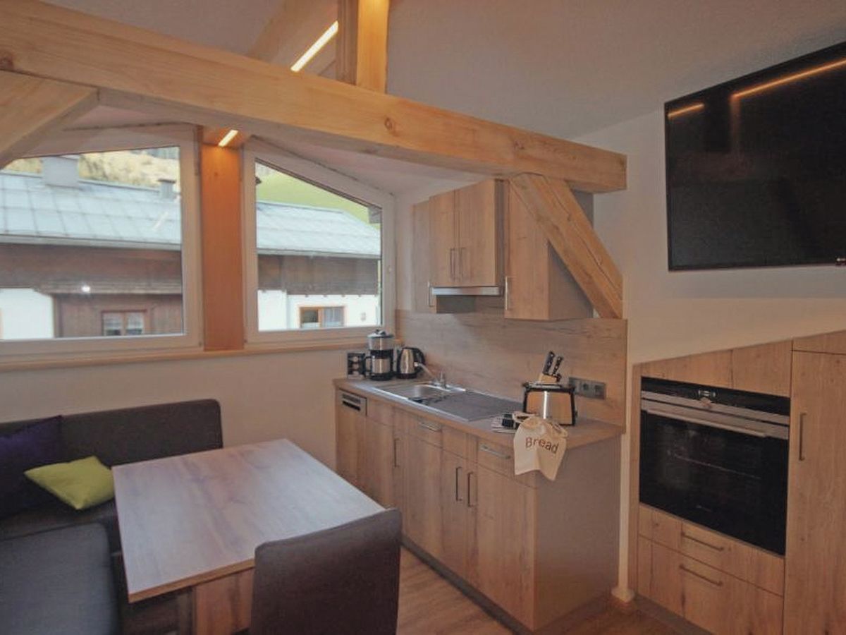 Una cocina compacta con armarios de madera, una mesa de comedor y un horno empotrado.