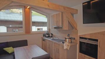 Una cocina compacta con armarios de madera, una mesa de comedor y un horno empotrado.