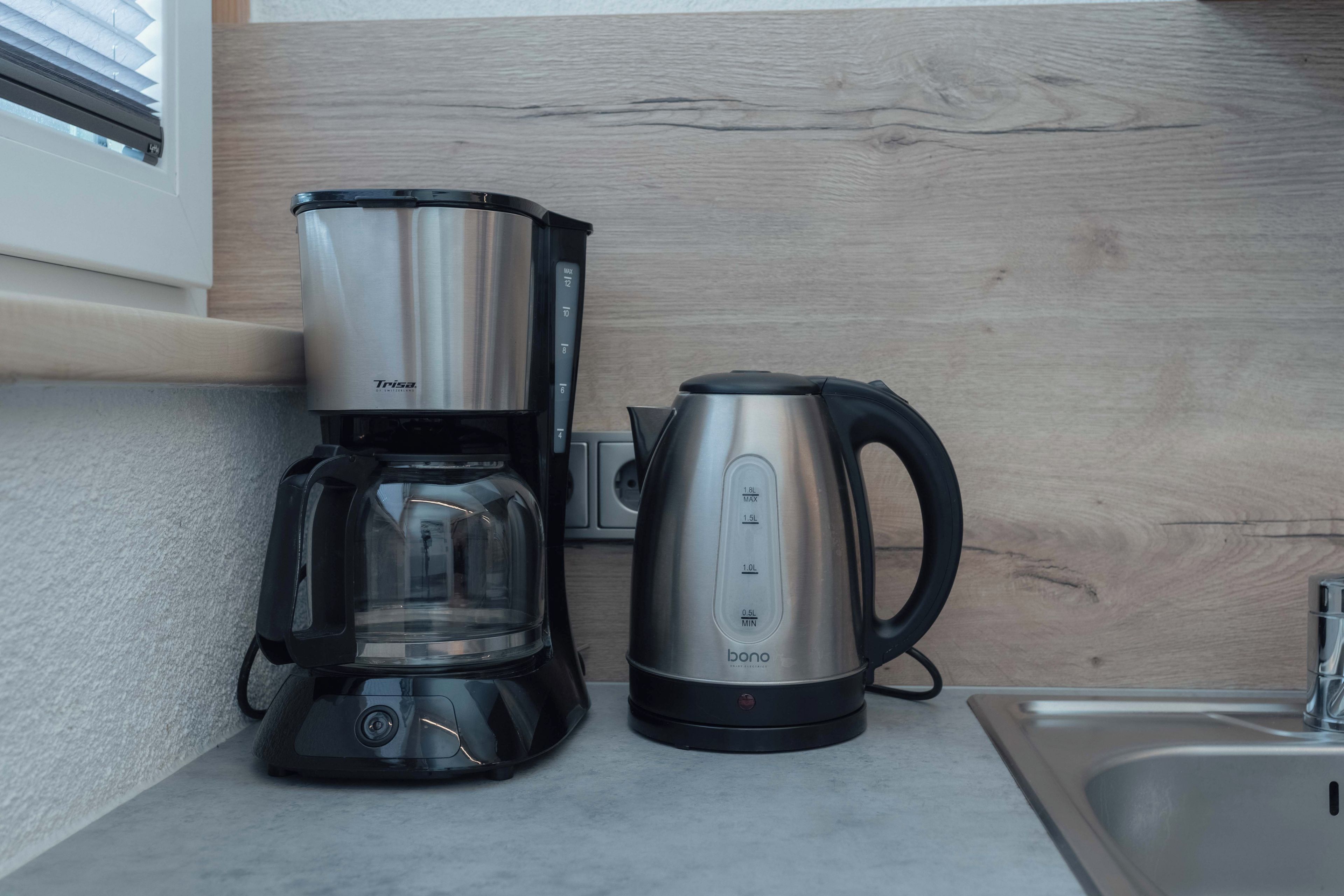 Cozinha com cafeteira e chaleira sobre a bancada.