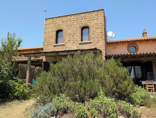 Un edificio de dos pisos con fachada de ladrillo, una antena parabólica y una pérgola de madera.