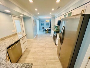 A kitchen with a granite countertop, stainless steel appliances, and a wooden floor. - Your Private Florida Escape - Stunning Pool Home (Fort Myers Beach)