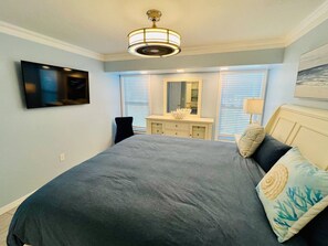 A bedroom with a bed, a dresser, a mirror, a television, and a ceiling fan. - Your Private Florida Escape - Stunning Pool Home (Fort Myers Beach)
