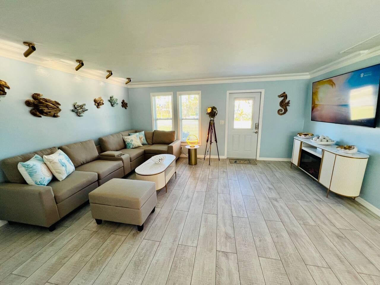 A spacious living room with a sectional sofa, a coffee table, and a TV mounted on the wall.