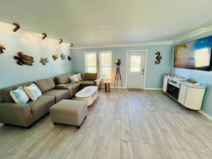 A spacious living room with a sectional sofa, a coffee table, and a TV mounted on the wall. - Your Private Florida Escape - Stunning Pool Home (Fort Myers Beach)
