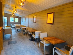 A restaurant with wooden walls and tables, featuring framed artwork on the walls.