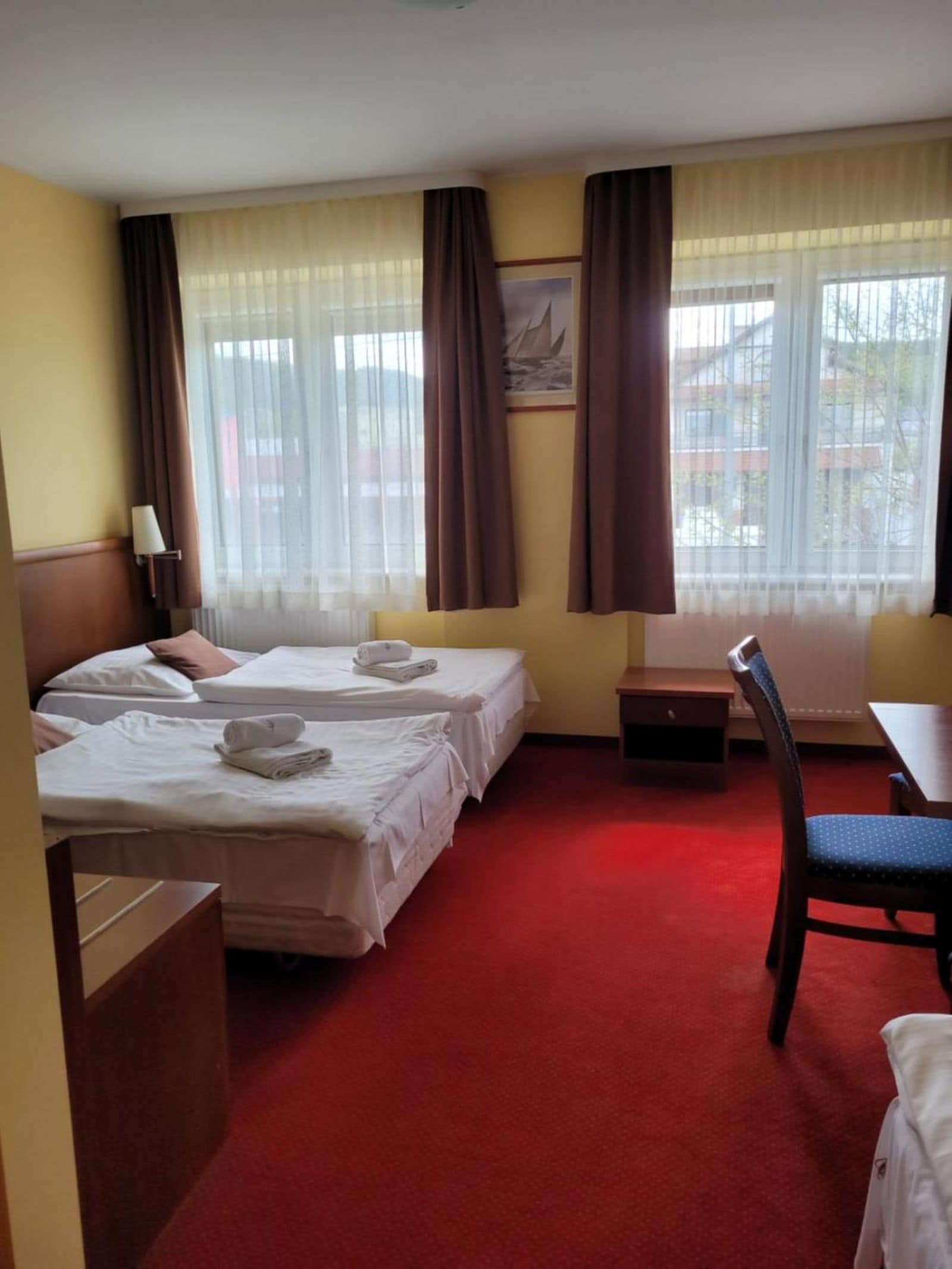 Una habitación de hotel con dos camas, un escritorio, una silla y una ventana con cortinas.