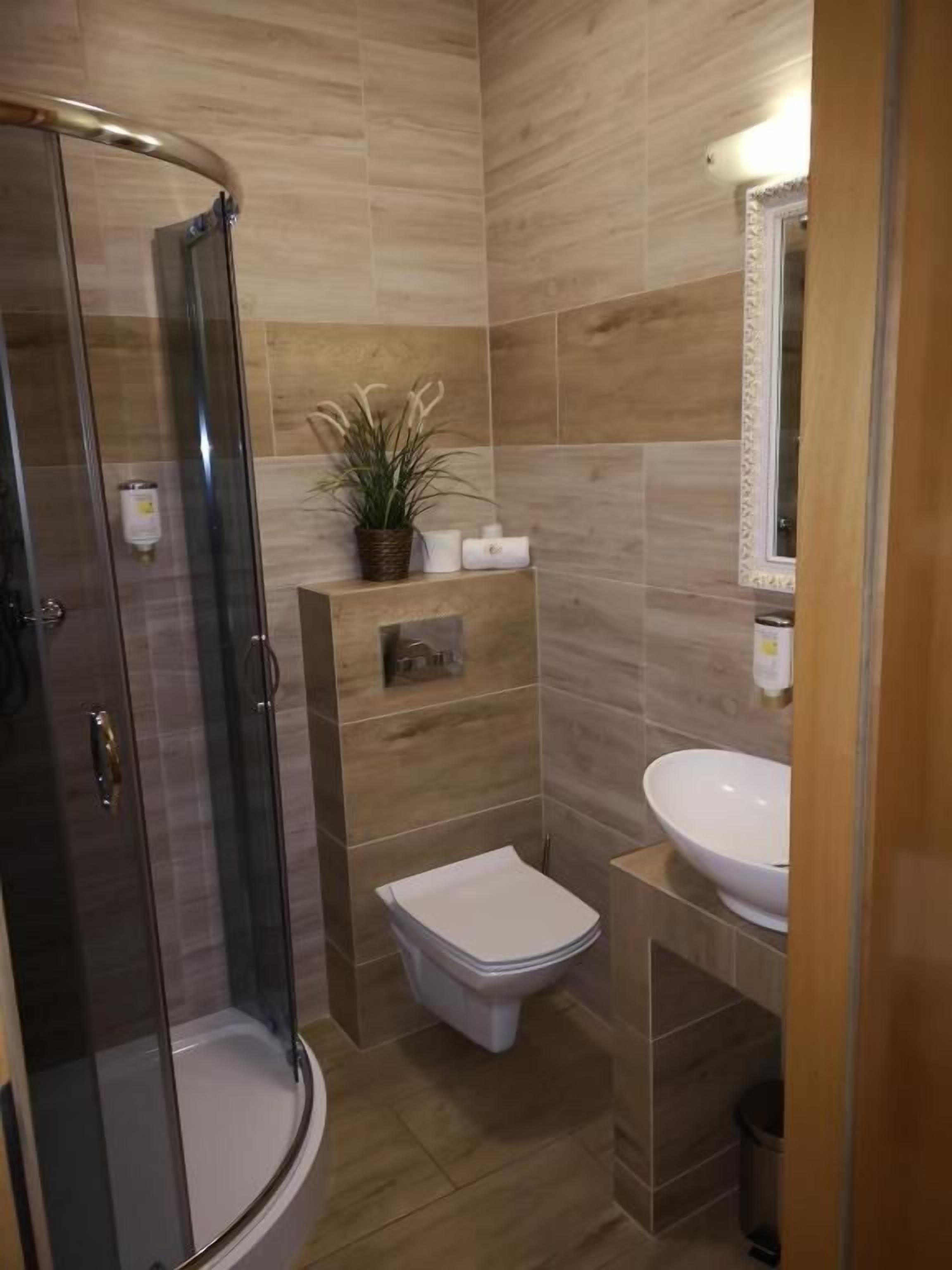 A bathroom with a glass-enclosed shower, a toilet, and a sink.