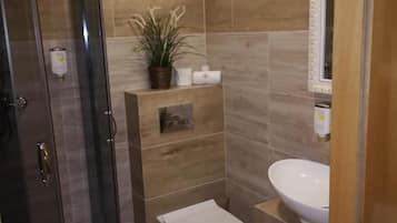 A bathroom with a glass-enclosed shower, a toilet, and a sink.