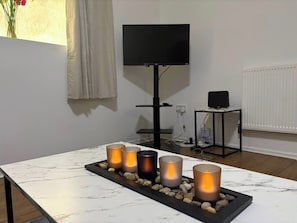 Ein Zimmer mit einem Marmortisch, Kerzen, einem Fernseher und einer Heizung.