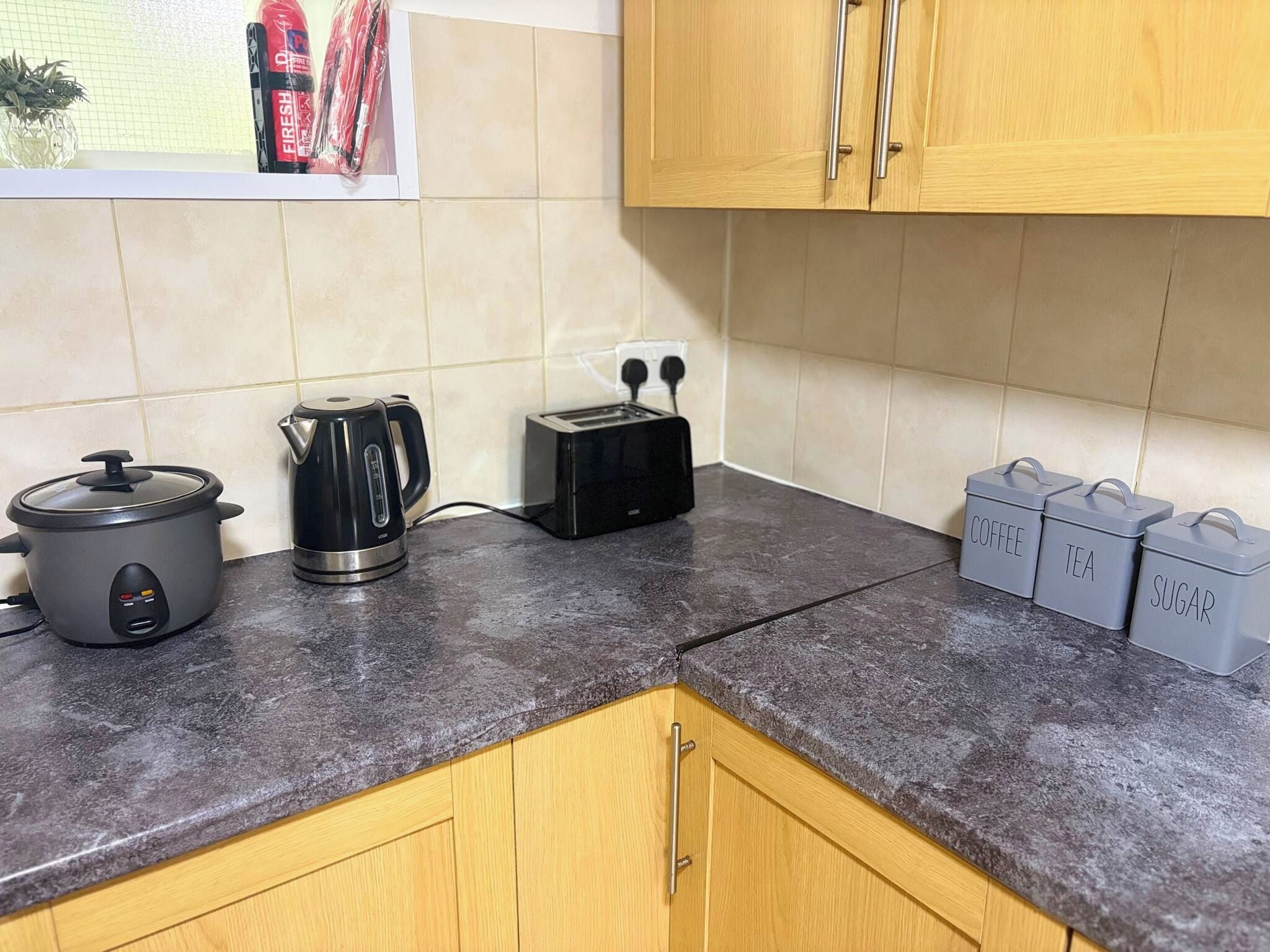 A kitchen with a stove, toaster, and containers labeled for coffee, tea, and sugar.