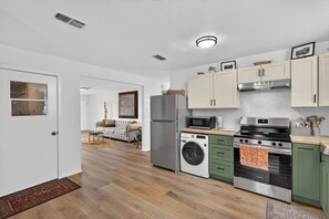 A compact kitchen with a washing machine, microwave, and stove. - Cozy 3BR Home Base | Coffee Bar | Massive Backyard (Abilene)