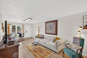 A living room with a sofa, armchair, coffee table, and a painting on the wall. - Cozy 3BR Home Base | Coffee Bar | Massive Backyard (Abilene)