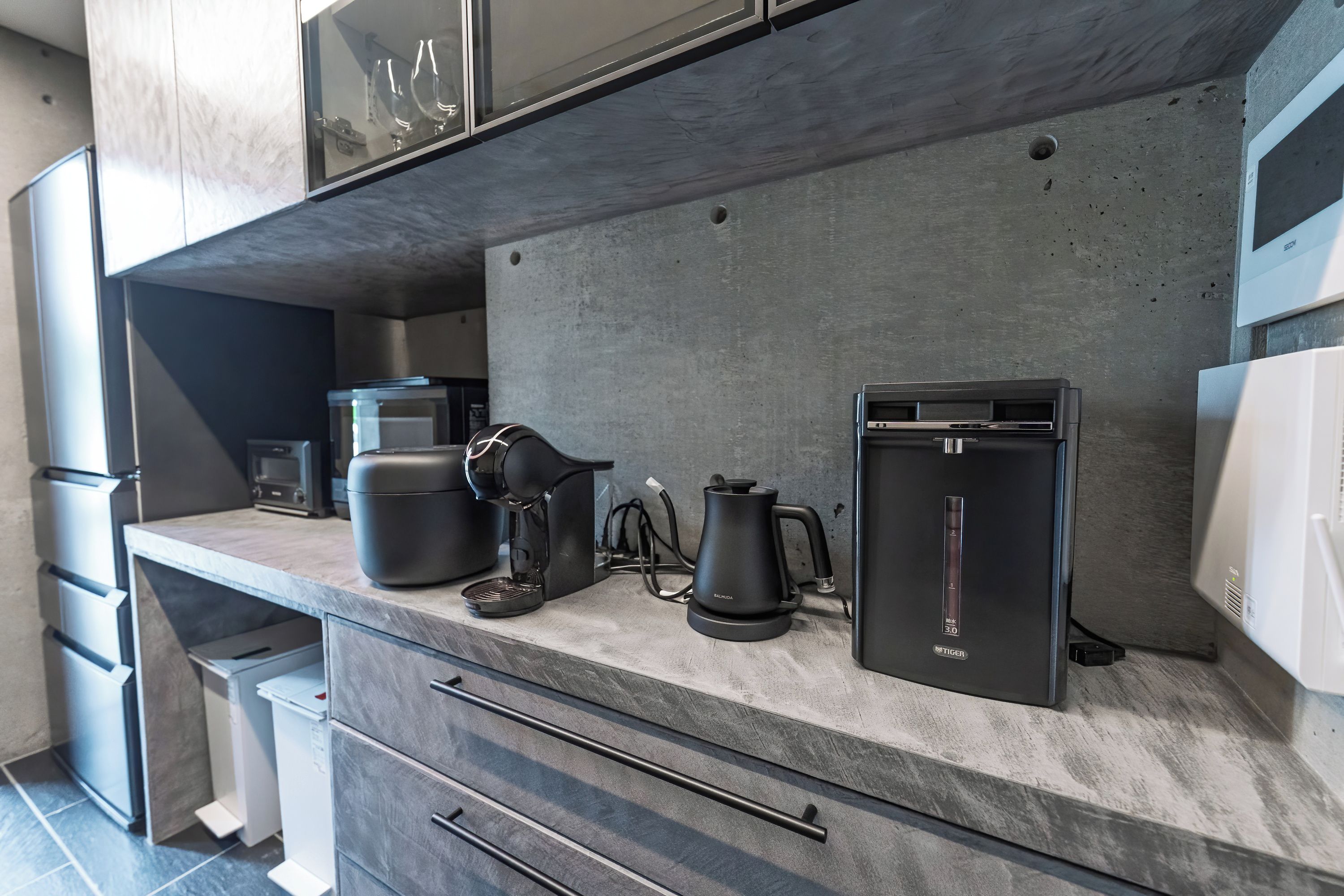 Eine moderne Küche mit integrierter Kaffeemaschine, Wasserkocher und Kühlschrank.