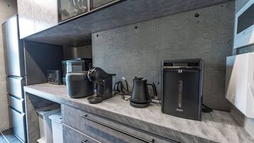 Eine moderne Küche mit integrierter Kaffeemaschine, Wasserkocher und Kühlschrank.