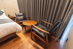 A hotel room with a bed, two chairs, a small table, and a curtain. - CASA MIYAKO II PREMIUM (Miyakojima)