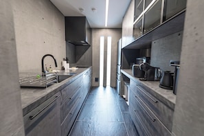 A modern kitchen with a central island, built-in appliances, and a minimalist design. - CASA MIYAKO II PREMIUM (Miyakojima)