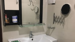 Une salle de bain avec un lavabo blanc, un meuble-lavabo en bois, un miroir et un porte-serviettes.