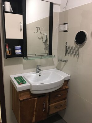 Une salle de bain avec un lavabo blanc, un meuble-lavabo en bois, un miroir et un porte-serviettes.