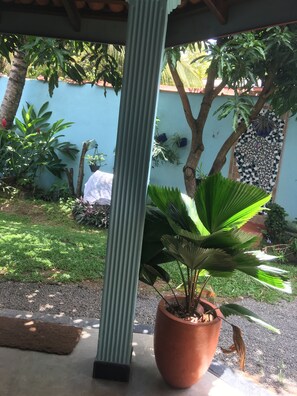 Un espace jardin agrémenté de diverses plantes en pot, d’une colonne en métal et d’un mur recouvert de carreaux.