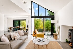 A modern living room with a sofa, coffee table, and a guitar. - Palm Beach House | 5 Bed by Pett Level Beach - Pass the Keys (Hastings)