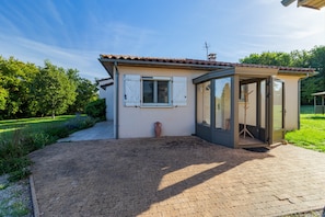 A small house with a tiled roof, a garden, and a glass door leading to an interior space. - Lou Poutou du Levant - maison avec jardin privé (Gramat)