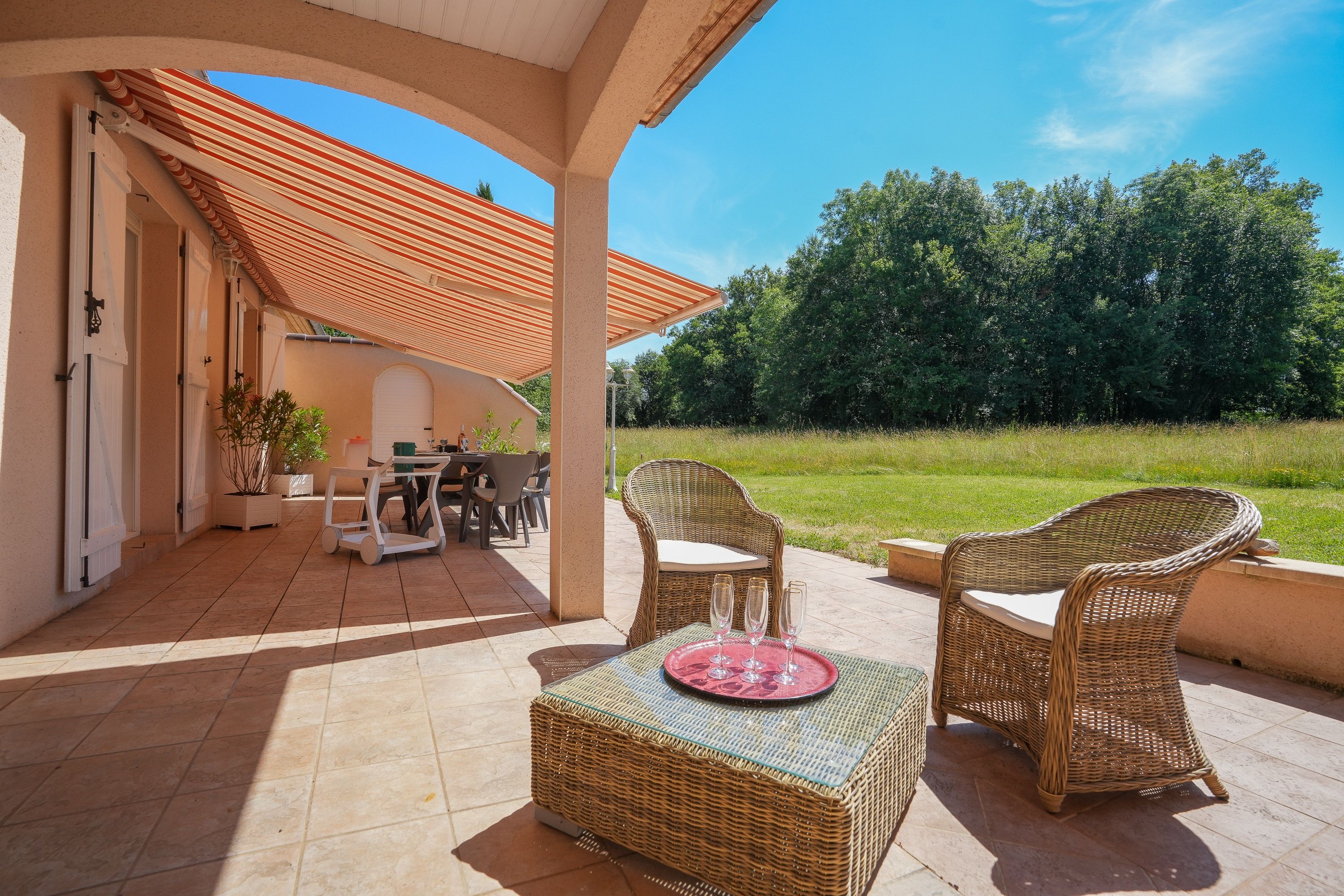 Une terrasse extérieure aménagée avec des meubles en osier, une table et des chaises.