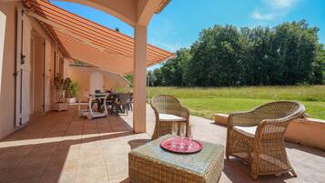 Une terrasse extérieure aménagée avec des meubles en osier, une table et des chaises.