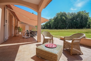 An outdoor patio with wicker furniture, a table, and chairs. - Lou Poutou du Levant - maison avec jardin privé (Gramat)