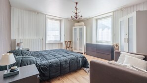 Une chambre à coucher avec un lit, une chaise, un bureau et une armoire.