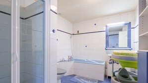 Une salle de bain avec douche, toilettes et lavabo.