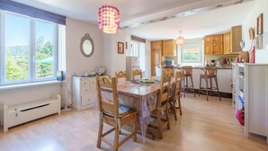 Une cuisine spacieuse avec des meubles en bois, une table à manger avec des chaises et une grande fenêtre offrant une vue sur l’extérieur.