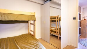 Ein Schlafzimmer mit Etagenbett, Kleiderschrank und Spiegel.