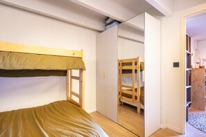 Ein Schlafzimmer mit Etagenbett, Kleiderschrank und Spiegel.
