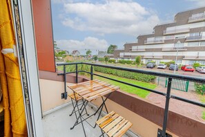 Ein Balkon mit Blick auf eine Wohngegend, einem Tisch und einem Stuhl.