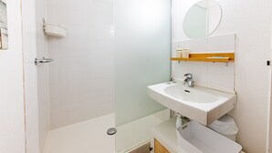 Een moderne badkamer met een douche, wastafel en spiegel.