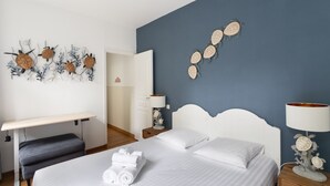 Une chambre d’hôtel avec un lit, un bureau et un mur décoré d’œuvres d’art.