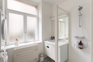 Une salle de bain avec une fenêtre, une douche, un lavabo et des toilettes.