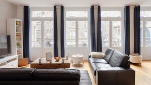 A modern living room with a leather sofa, a coffee table, and a television. - La Croix du Fief - Dans Intra Muros (Saint-Malo)