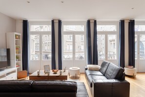 Un salon moderne avec un canapé en cuir, une table basse et un téléviseur.