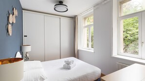 A bedroom with a bed, a bedside table, a lamp, a window, and a wall with decorative items. - La Croix du Fief - Dans Intra Muros (Saint-Malo)