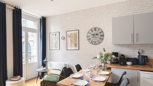 A modern kitchen with a dining table set for four, a coffee machine, and a clock on the wall. - La Croix du Fief - Dans Intra Muros (Saint-Malo)
